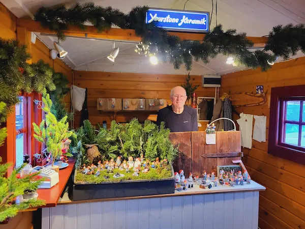 Bengt Yourstone står i butiken, Tomtebo, bakom disk, med Tomtefamiljen i Storskogen framför sig